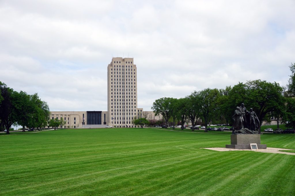 Outside the Bismarck capital building in Bismarck, North Dakota with a statue on the right