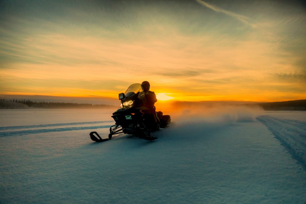 Man rides on a snowmobile during a sunset