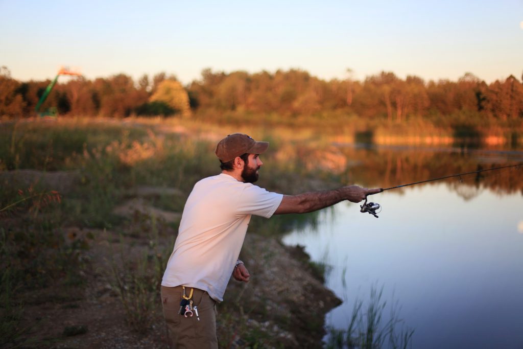 Man fishing in a pond near grass field in the Great Plains