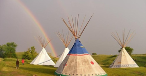three tipis with a rainbow in the background