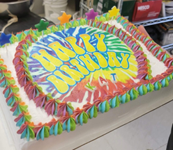 Sheet cake with rainbow color icing, happy birthday text and candles